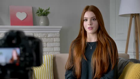 young red-haired girl blogger, smiling, talking at the camera, showing a new purchase, smartphone, application, green screen, chroma key, home comfort in the background. 60 fps