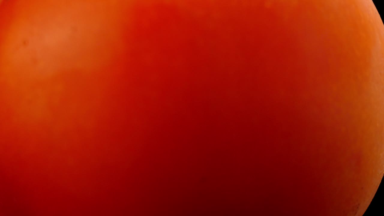 macro de primer plano de un tomate con un fondo negro que también parece un planeta de gas rojo