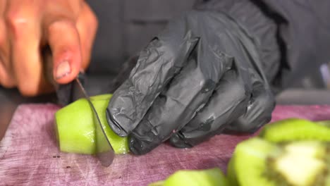 person cutting kiwi fruit