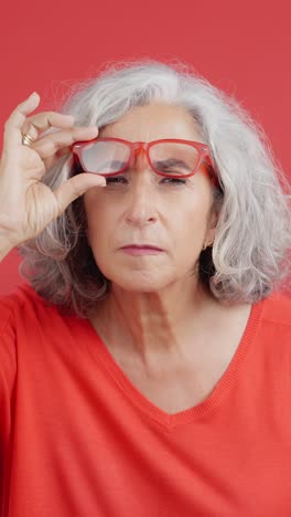 elderly woman with red glasses looking confused
