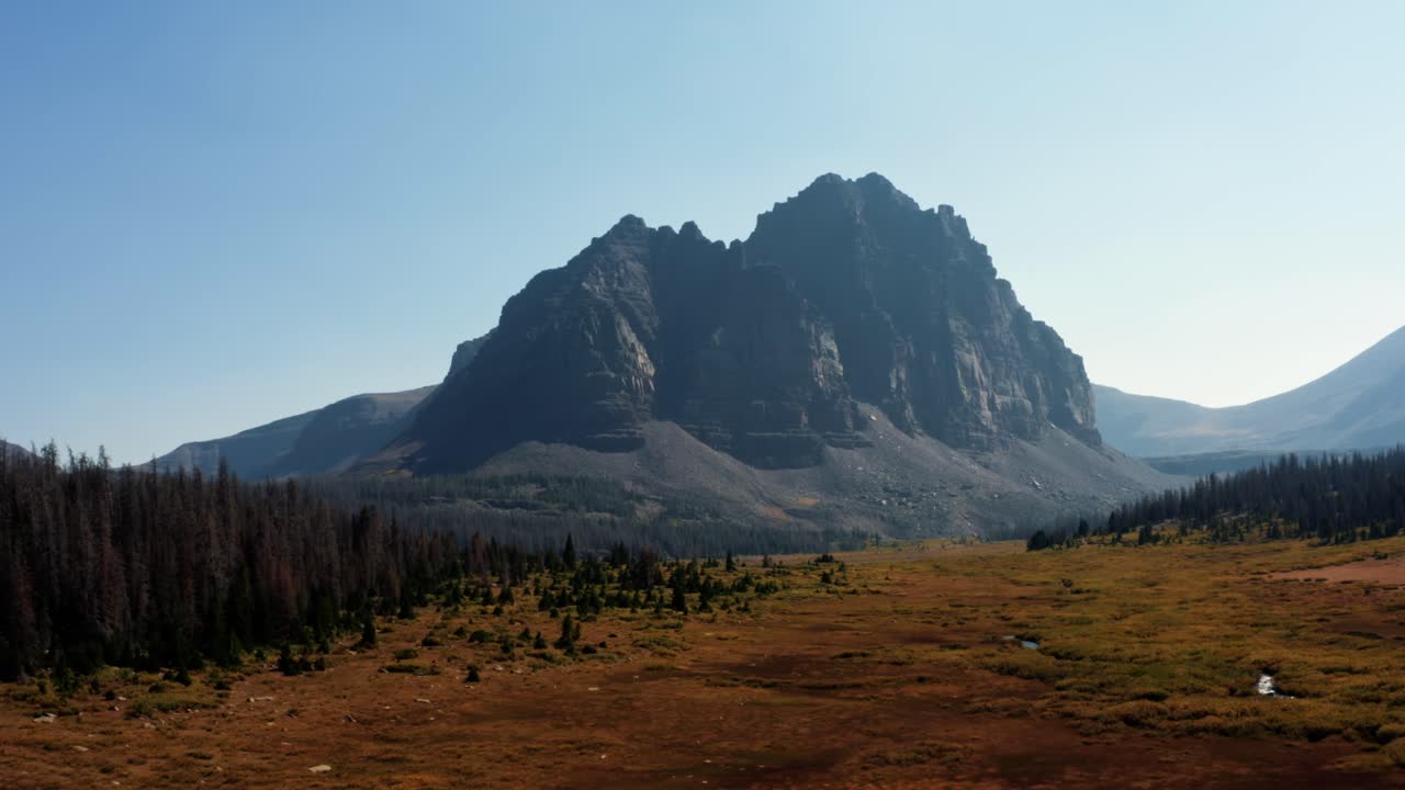 impresionante paisaje de drones aéreos naturaleza dolly en la toma de un gran prado con un pequeño arroyo con el hermoso lago del castillo rojo inferior y pico detrás en el bosque nacional de uinta alto en utah
