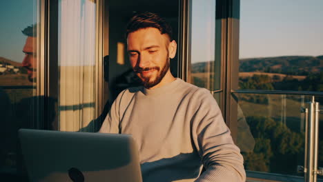man working remotely on a modern balcony with a scenic view