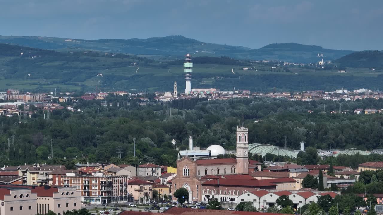 Aerial panning shot from left to right with Mavic 3, showing Verona Telecom Tower behind Basilica di Santa Teresa and Chiesa di San Michele Extra, viewed from Verona Fairgrounds