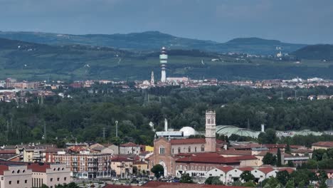 aerial panning shot from left to right with mavic 3, showing verona telecom tower behind basilica di santa teresa and chiesa di san michele extra, viewed from verona fairgrounds