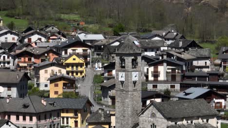 a dynamic aerial tracking footage of the clock tower in the middle of the town of villadossola, domodossola, and simplon pass