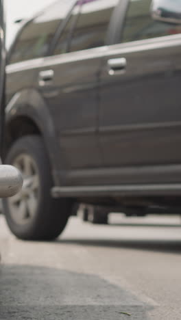 vehicles stand on street with heavy traffic jam in center of city. focus changes from wheel with rubber tire to big car changing lane on road closeup