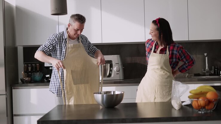 Coppia romantica a casa in cucina mentre si mette i grembiuli.