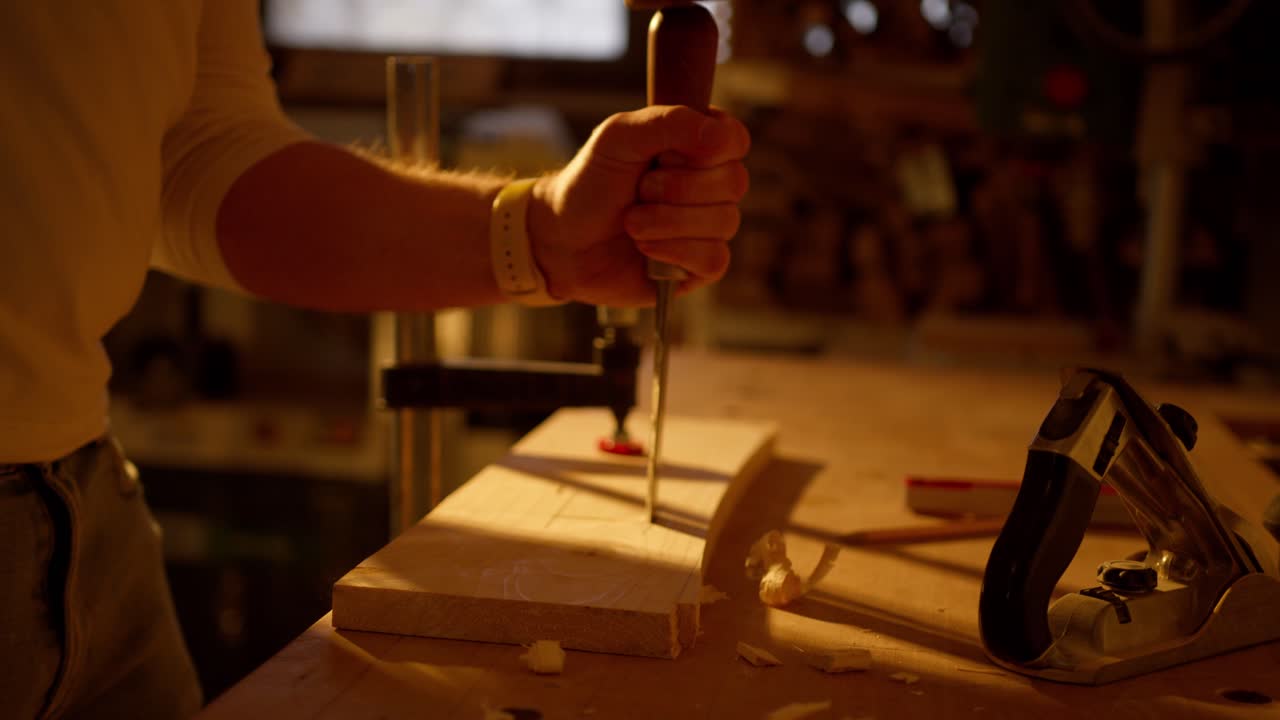 persona martillando papel de lija para separar piezas cortadas de una tabla de madera dentro del taller