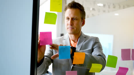 Businessman-writing-on-sticky-note-on-glass-wall-4k