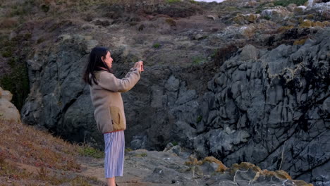 mujer alegre grabando el paisaje con su celular, para publicarlo en redes sociales, hermosa luz del atardecer buchupureo chile