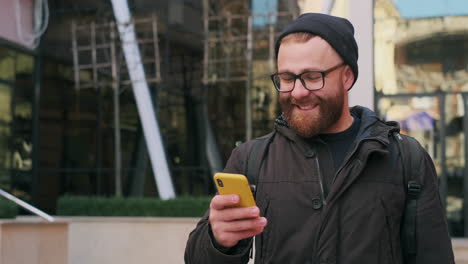 smiling man looking at his smartphone in an urban environment
