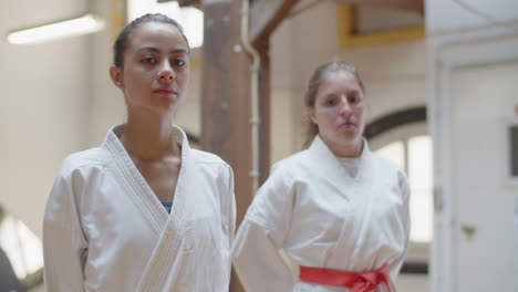 vista frontal de mujeres seguras y serias que atan cinturones en kimonos