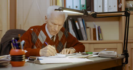 empresario senior escribiendo en papel en la mesa en la oficina 7