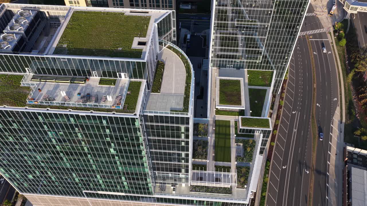 Centro moderno e futurista de Reston, Virgínia, com jardins verdes nos telhados, ruas da cidade e luz solar, mostrando arquitetura americana sustentável, design urbano e um distrito comercial limpo. Inclinação aérea para cima.