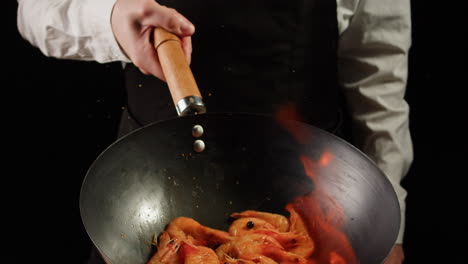 chef cooking shrimp in wok with fire