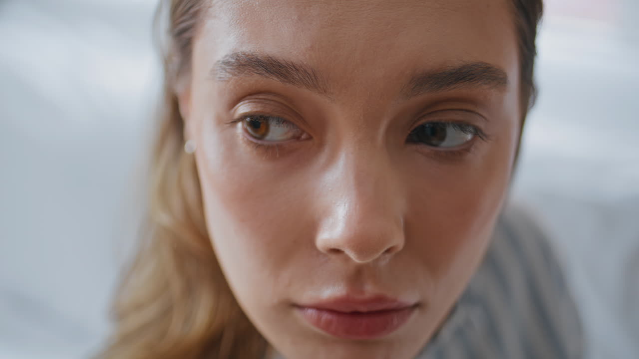 Closeup serious lady face showing worried expression in room. Melancholic girl