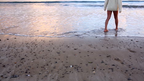 Woman-walking-along-the-water-at-sunset-and-paddling