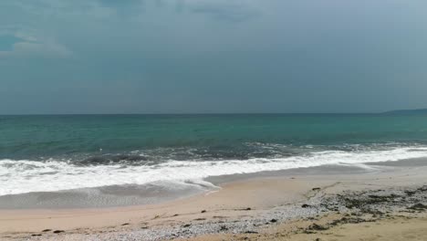 Drone-Volando-Bajo-A-La-Playa-Hacia-El-Mar,-Cielo-Nublado,-Agua-Oscura---Sozopol,-Bulgaria