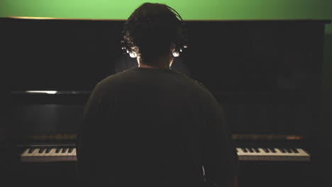 Desde-La-Vista-De-Un-Músico-Con-Auriculares-Tocando-El-Piano-En-Un-Estudio-Con-Poca-Luz