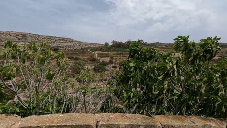 timelapse of passing by ruins of an ancient compound along a hillside during the daytime on a partially overcast day