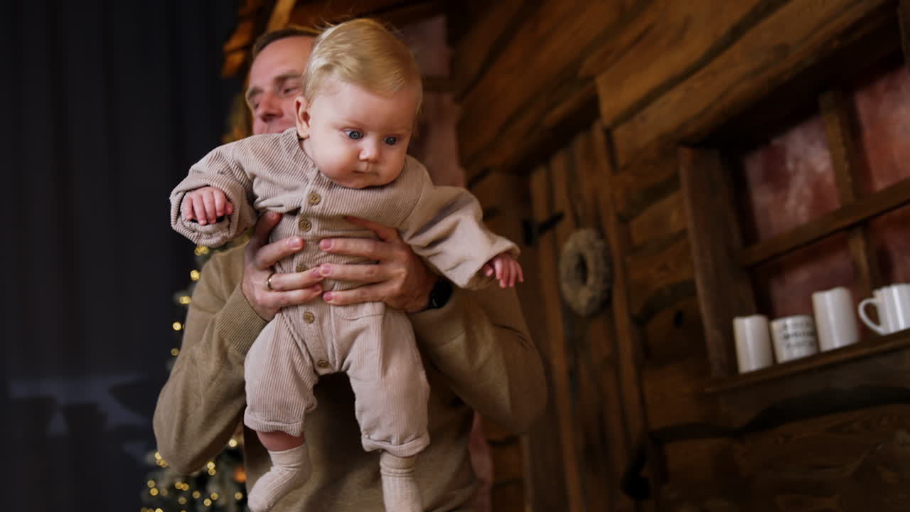 Daddy holding a little baby in hands. Father and infant son together. Man kissing the child tenderly.