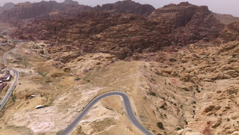 a estrada sinuosa de asfalto revela as montanhas de arenito da cidade de wadi musa, perto de petra, na jordânia.