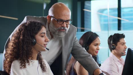 mujer del centro de llamadas india ocupada trabajando en la computadora interactuando con el viejo jefe masculino
