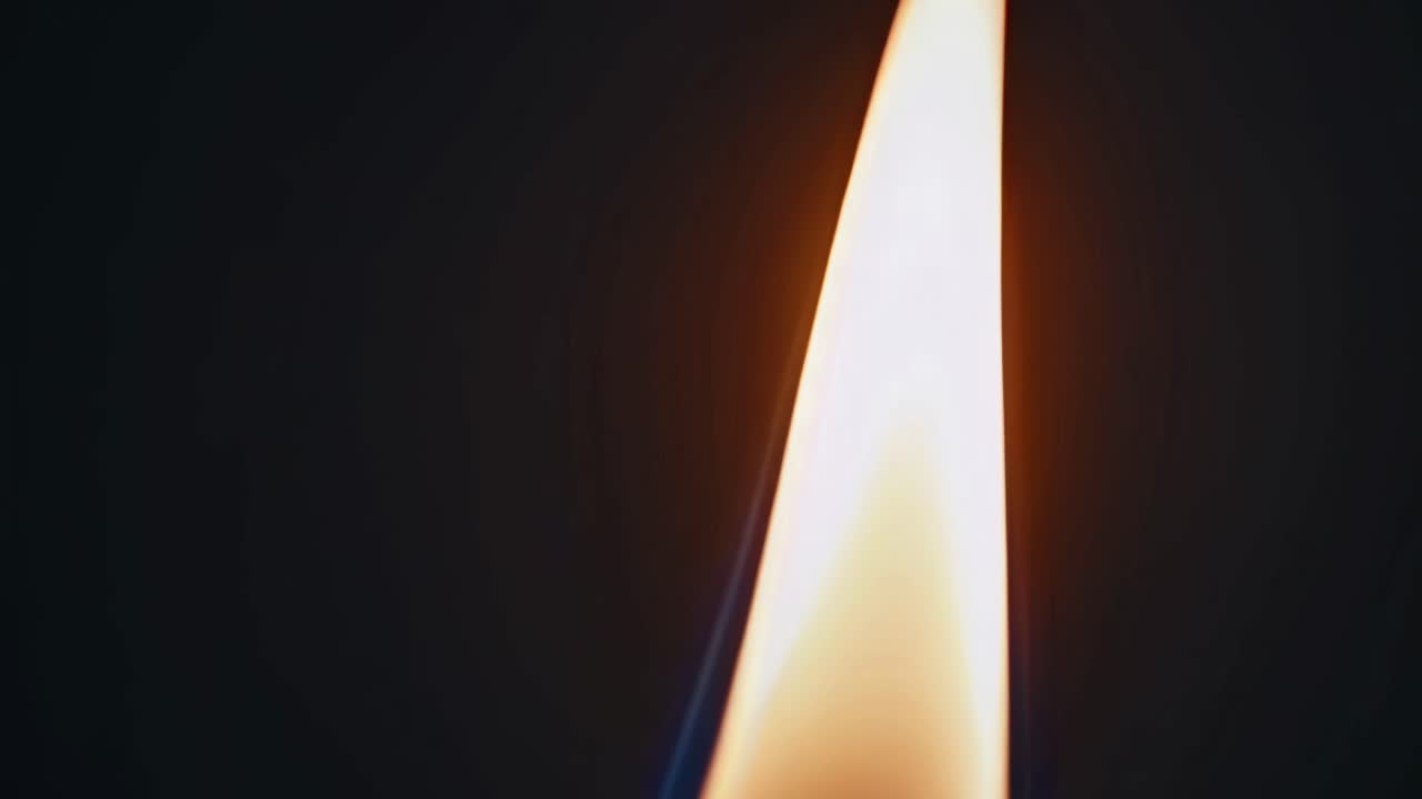 Video ravvicinato di una fiamma di candela su sfondo scuro, ripreso da un'angolazione laterale