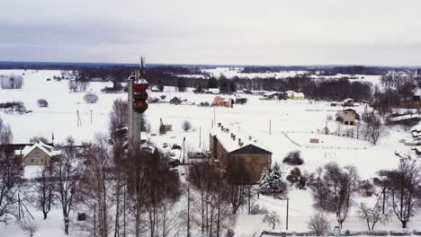 aerial view flying towards cellular station on snow covered rural german village countryside