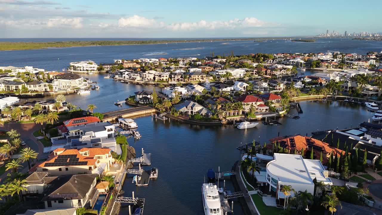 Drone footage captures luxury waterfront homes and boats in Gold Coast, Australia, under clear skies with vibrant lighting
