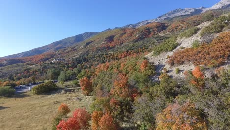 A-drone-flies-near-the-rocks-and-slopes-of-the-mountain-near-Dry-Creek-Trailhead-in-Alpine,-Utah-as-leaves-change-into-bright-fall-colors