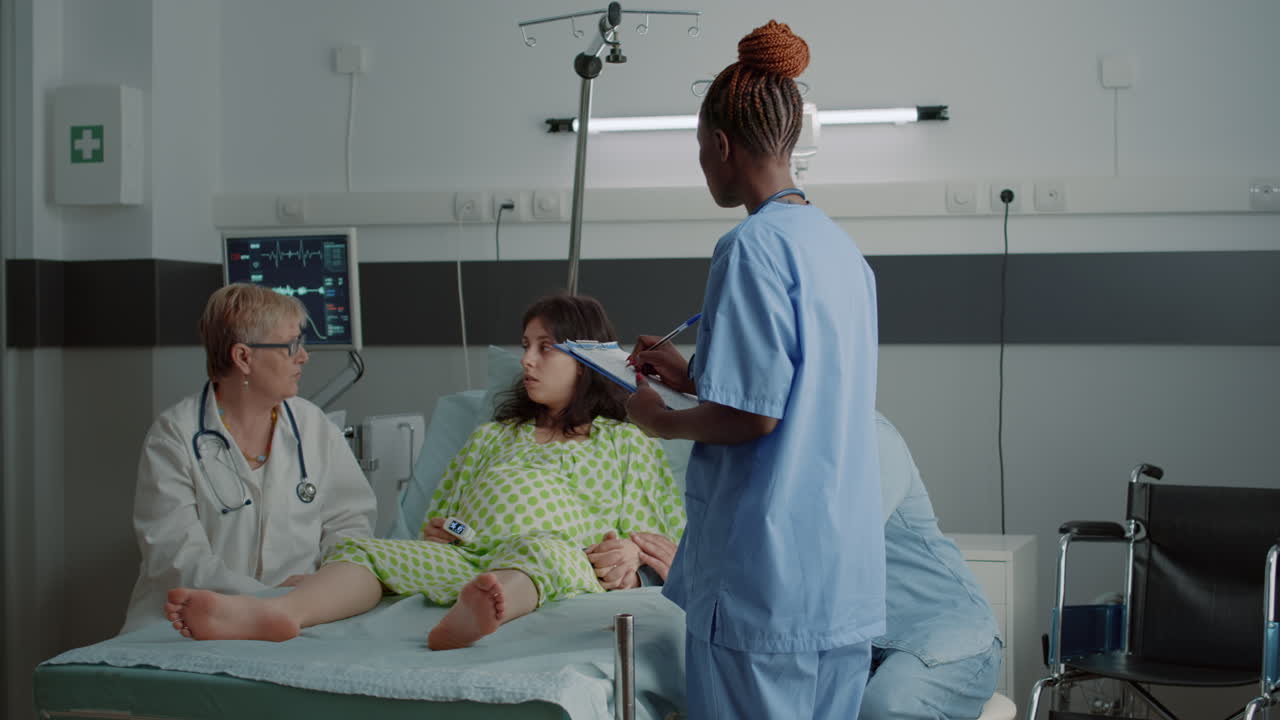 Equipe medica multietnica che parla con una donna incinta