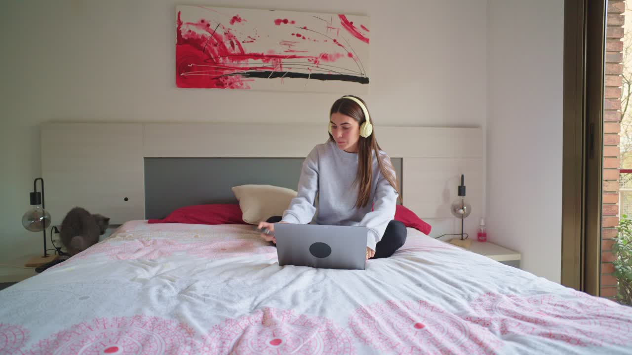 Woman with cat using laptop on bed