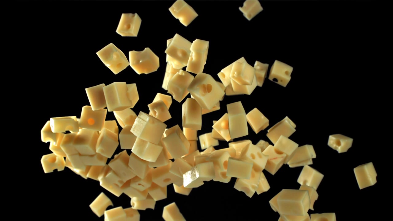 Cubetti di formaggio che cadono al rallentatore su sfondo nero