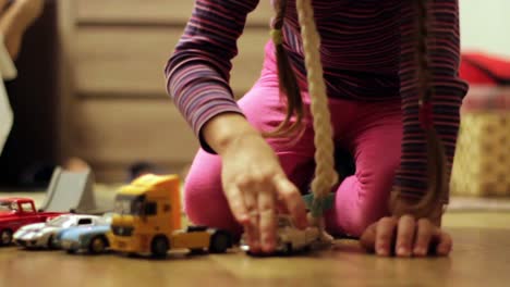 child girl plays with a small toy cars