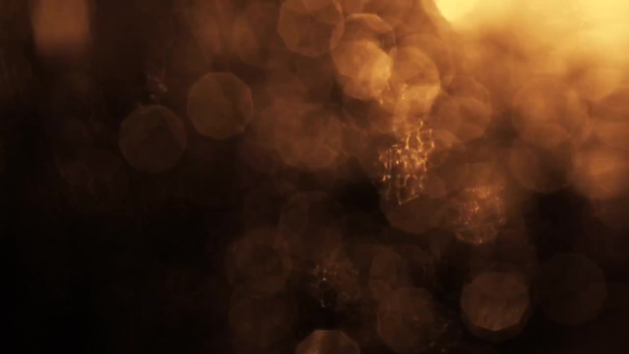 Gyllne bokeh-lyspartikler som flyter på svart bakgrunn
