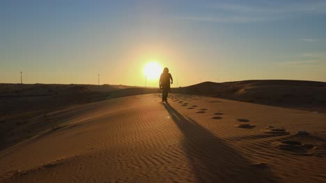 Silhouette:-A-man-walks-alone-in-the-Arabian-Desert-of-the-United-Arab-Emirates,-landscape-video-of-the-gulf-desert,-UAE-desert