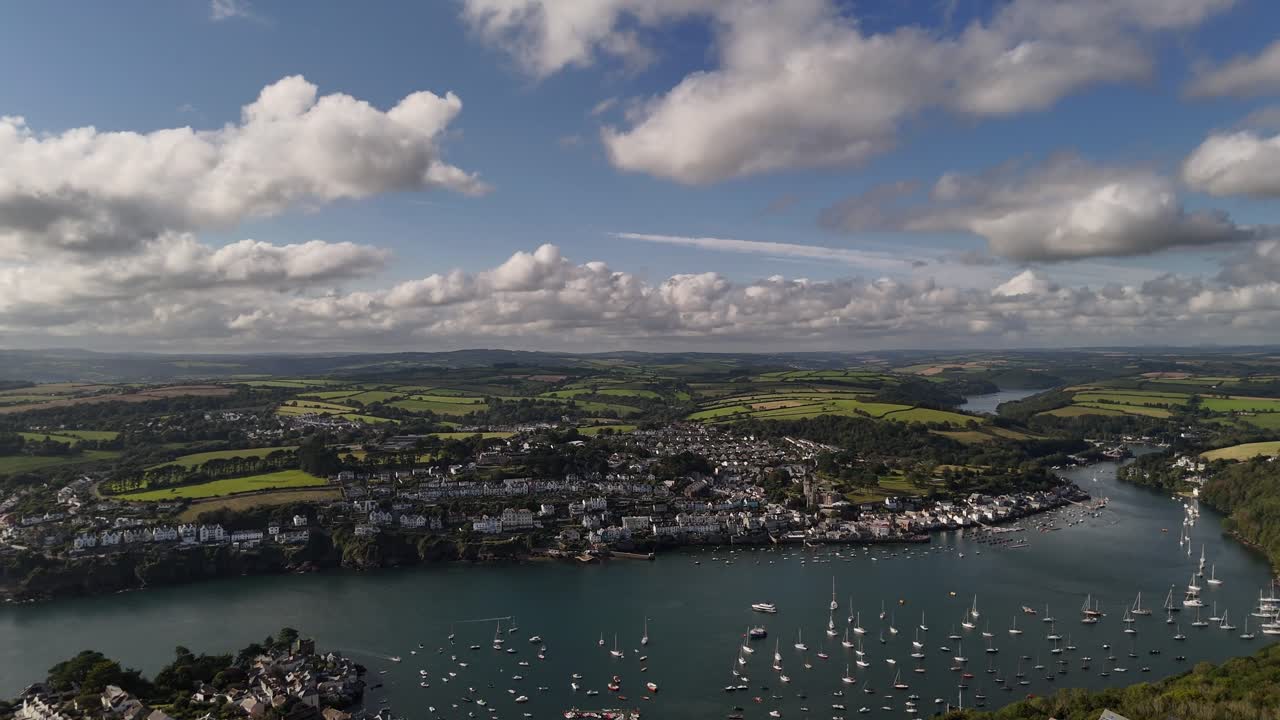 Sideways pan left across Cornwall town of Fowey. Ultra-wide shot of riverside town in England.