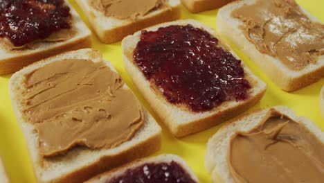 Close-up-of-multiple-peanut-butter-and-jelly-sandwiches-on-yellow-surface