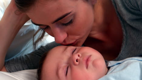 Mother-lying-with-sleeping-baby-boy-on-bed