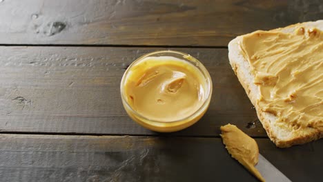 Video-of-close-up-of-toast-with-peanut-butter-on-wooden-background