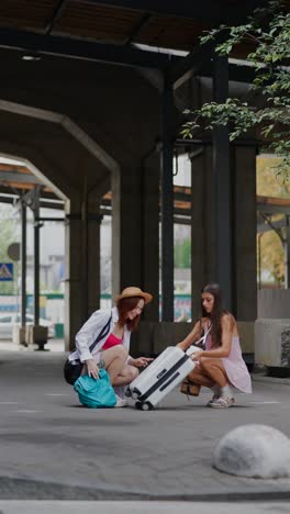 two women inspecting luggage at a train station