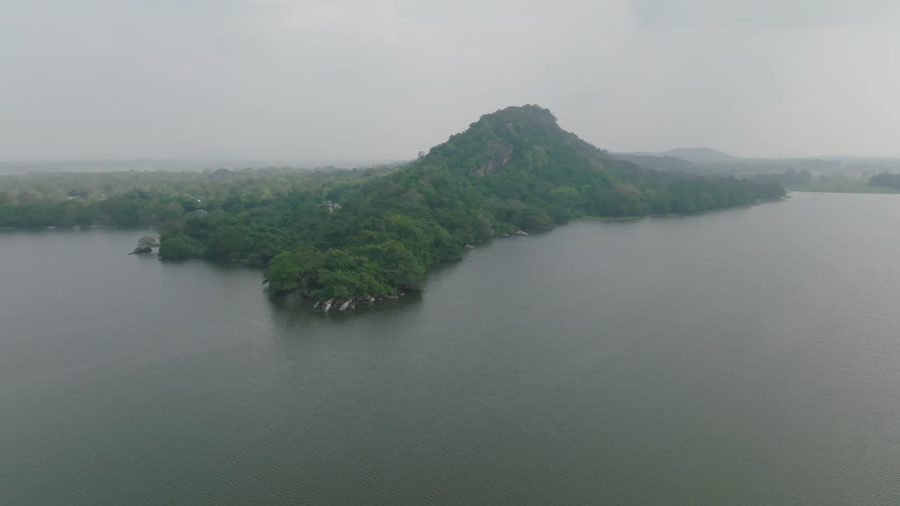 Stunning view of an isolated hill covered in dense vegetation and bordered by calm waters