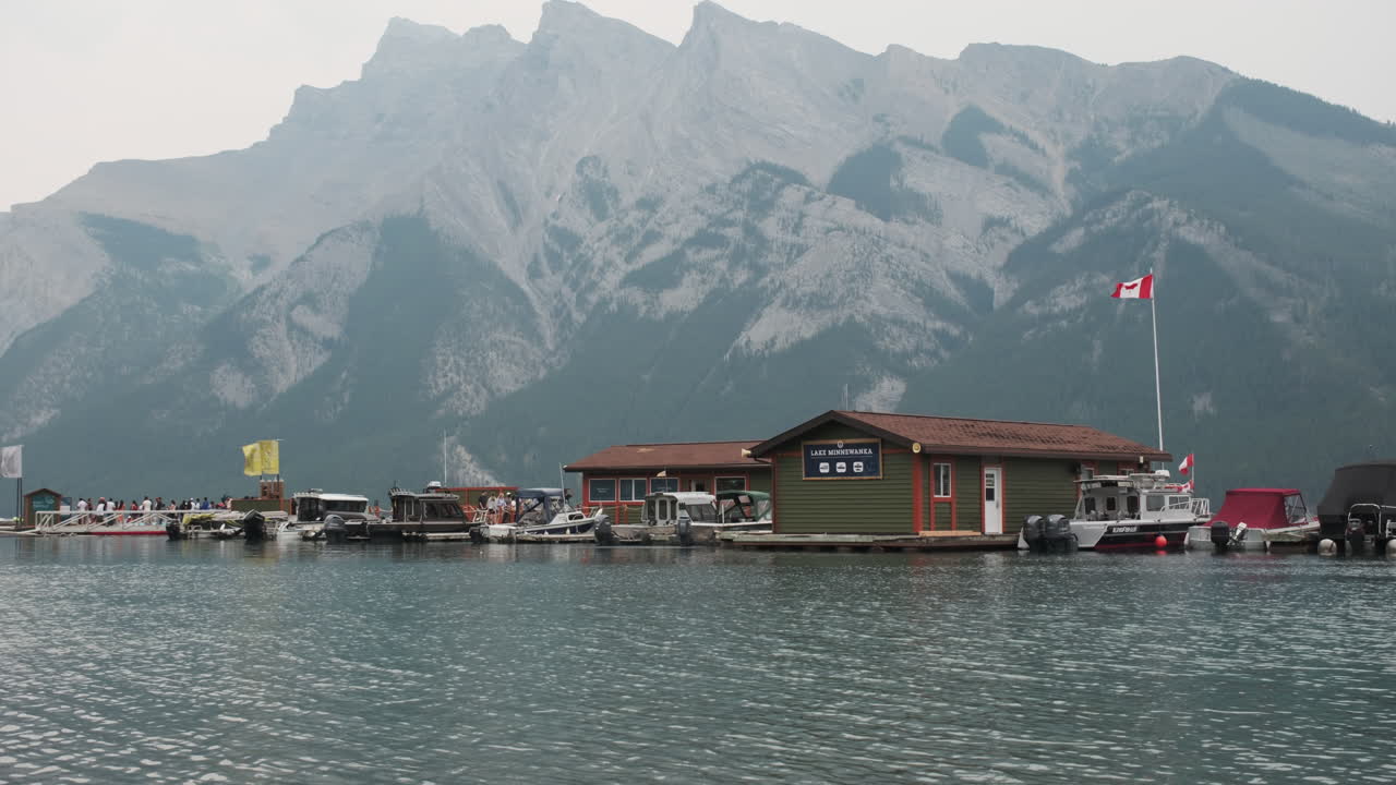 The Canadian flag waves over Lake Minnewanka in Banff, with majestic mountains as backdrop
