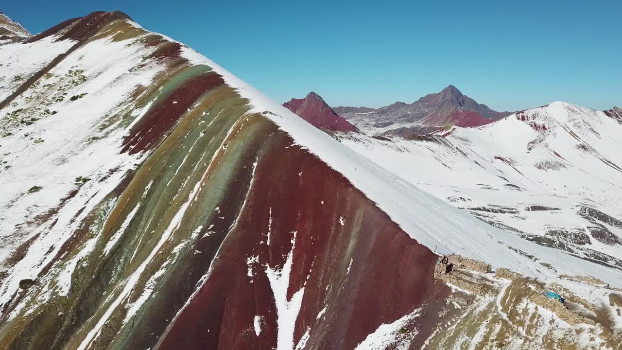 Aerial, rising, drone shot over snowy Vinicunca rainbow mountain, sunny day in Pitumarca, Andes mountains, Peru, South America