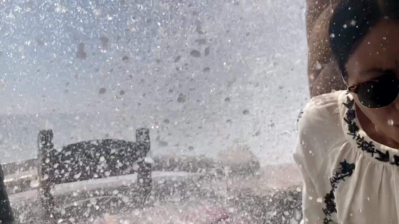 Young woman is hilariously soaked by a huge rouge wave while on vacation