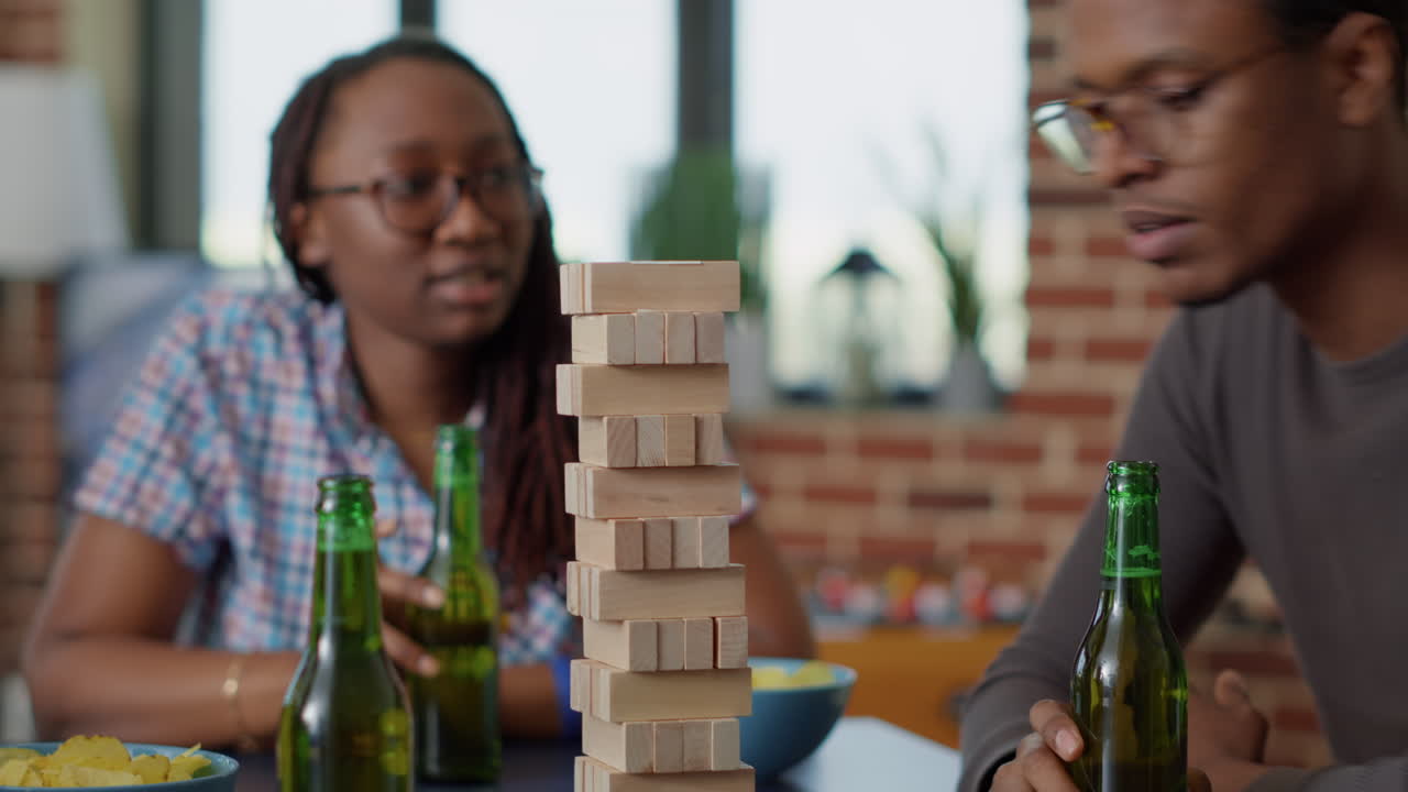 Group of cheerful people having fun with wooden tower play