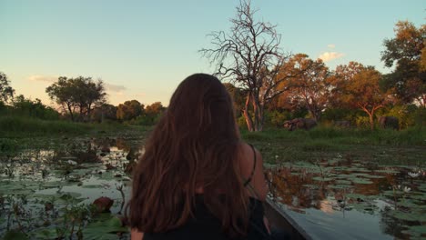 A-young-woman-sitting-at-the-front-of-a-boat-moving-through-a-swamp