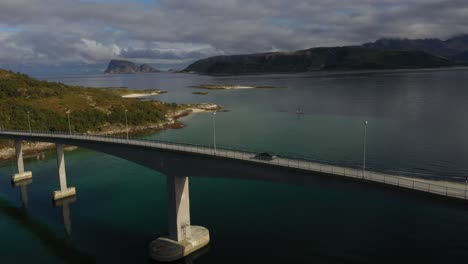 car driving across a bridge in arctic norway surrounded by the fjord and the mountains