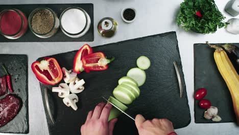 Slow-motion-footage-of-a-chef-cutting-vegetables-on-a-black-cutting-board-in-the-kitchen
